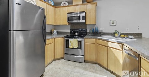 A kitchen with wooden cabinets and a stainless steel refrigerator.