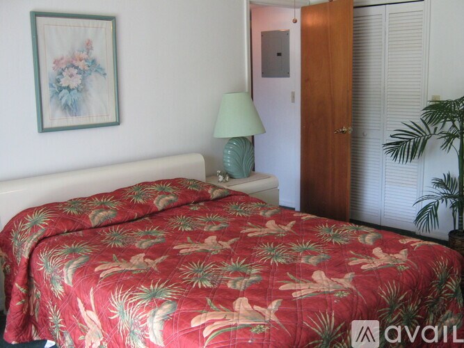 A bed with a red floral comforter is in the foreground of the image.