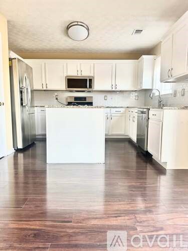 A kitchen with white cabinets and a wooden floor.