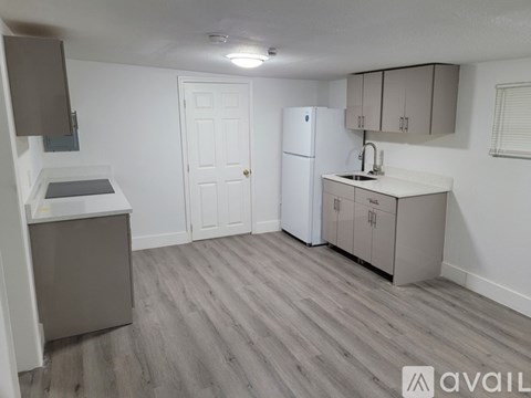A kitchen with a white fridge, cabinets, and a sink.