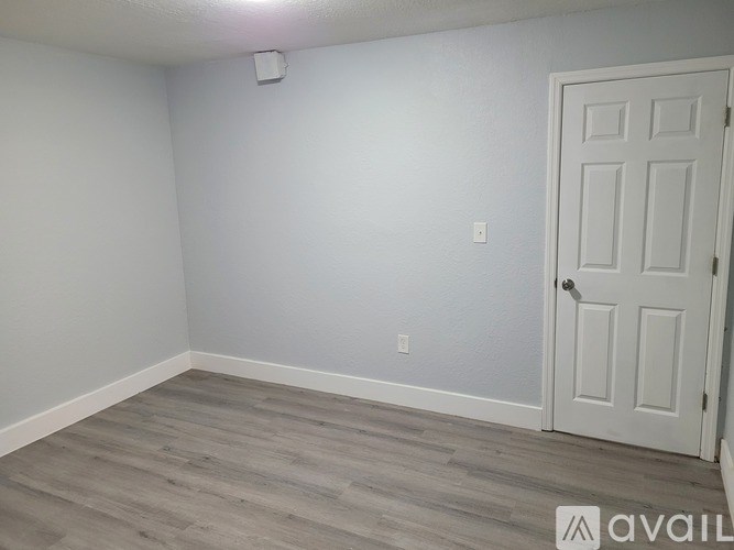 A room with a white door and grey flooring.