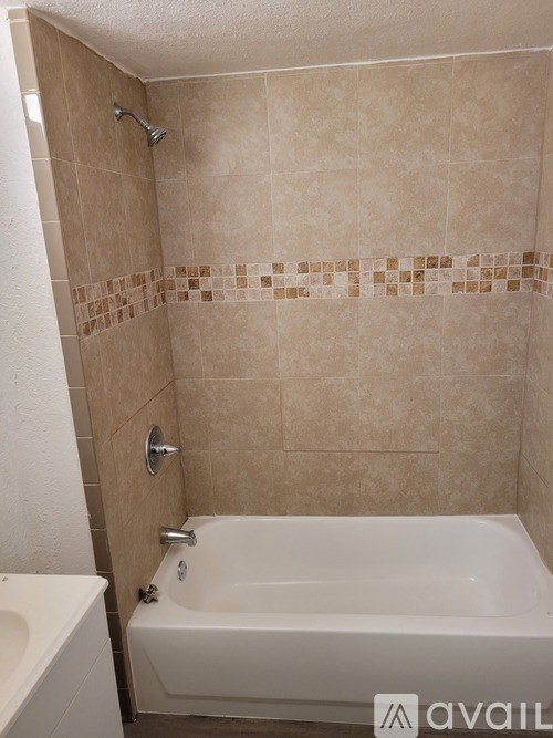 A bathroom with a beige tiled shower and a white bathtub.