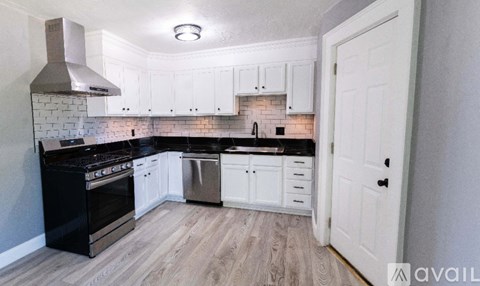 A kitchen with black appliances and white cabinets.