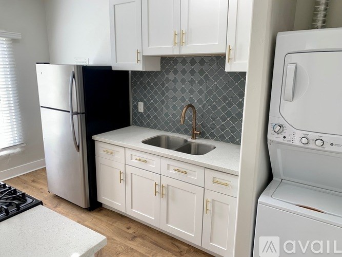 A kitchen with white cabinets and a black refrigerator.