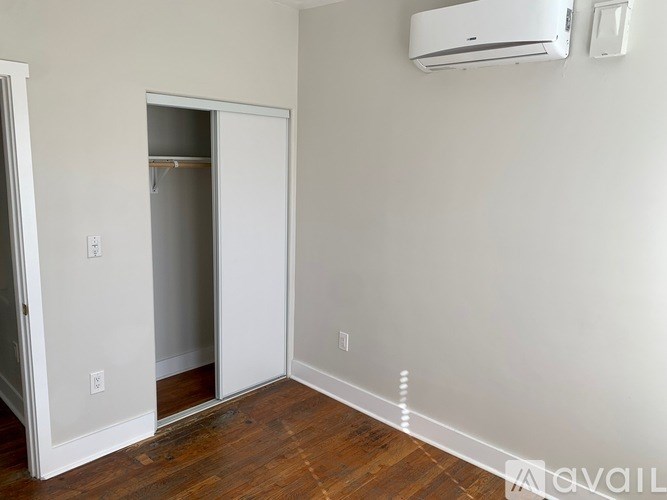 A room with a white door and a wall-mounted air conditioner.