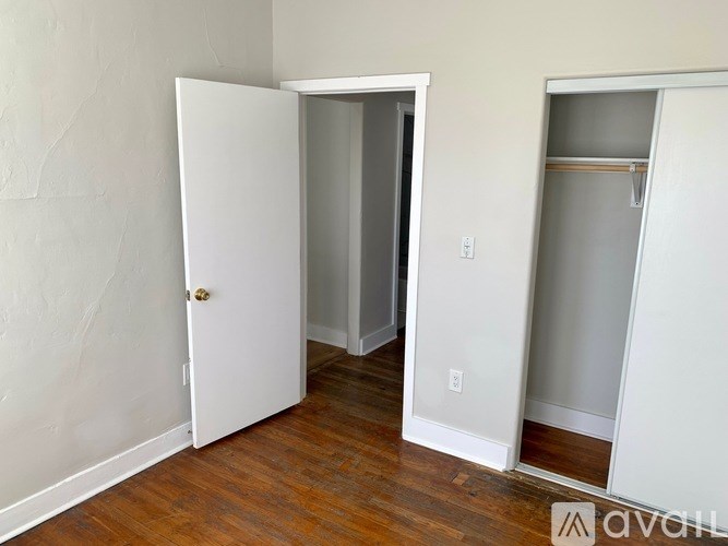 A room with a white door and a white closet with a shelf.