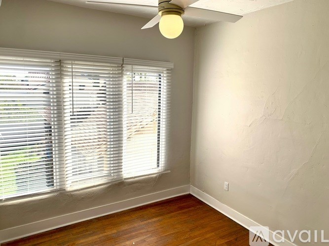 A room with a window covered by white blinds and a ceiling fan.