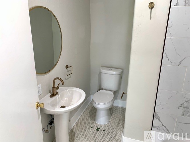 A white bathroom with a toilet, sink and mirror.