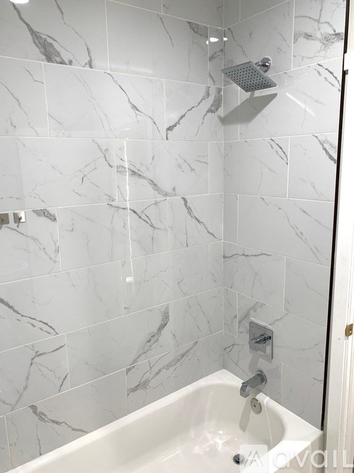 A white bathroom with a marble tile wall.