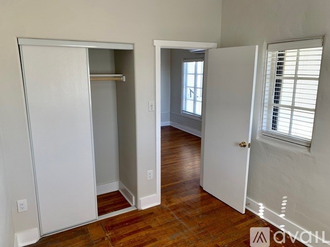 A white closet with a mirror and a white door is open.