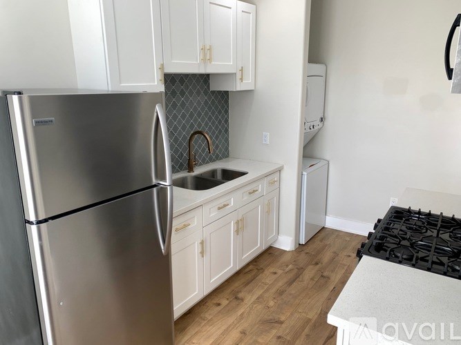 A kitchen with a stainless steel refrigerator and white cabinets.