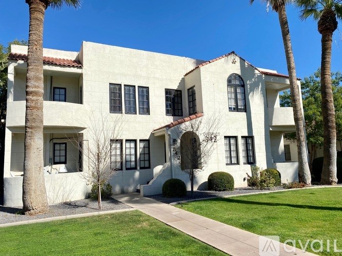 A white house with a red tile roof and a palm tree in front.
