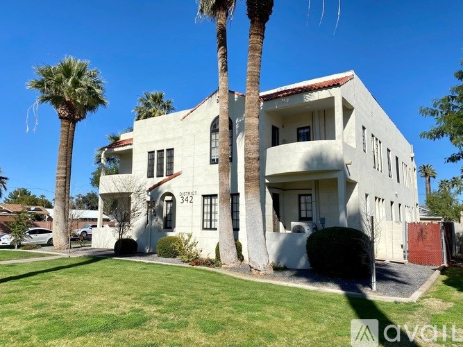 A white house with a red roof and a palm tree in front.