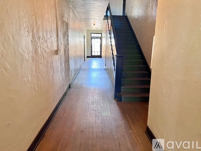 A long hallway with wooden floors and a staircase on the right.