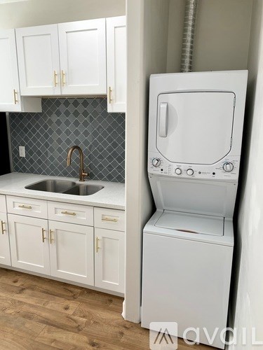 A white washing machine sits next to a sink in a kitchen.