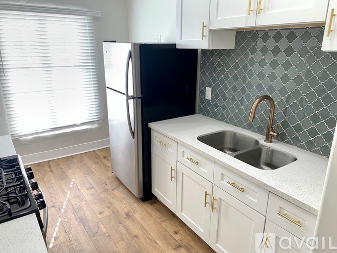 A kitchen with a black refrigerator, white cabinets, and a black stove top.
