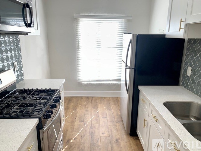 A kitchen with a black fridge, white cabinets, and a stove top oven.