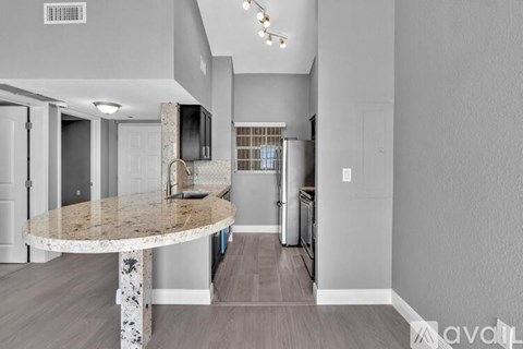 A kitchen with a granite countertop and a refrigerator with a stainless steel finish.