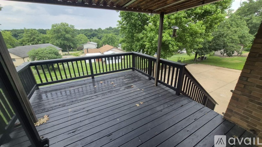 A wooden deck with a railing and a view of a residential area.