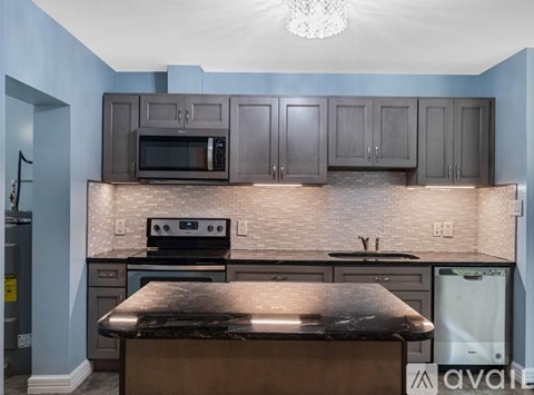 A kitchen with a black countertop and a brick backsplash.