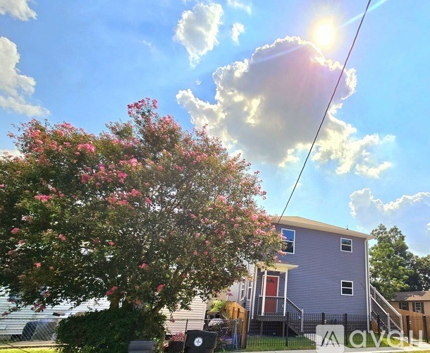 A house with a blue exterior and a tree with pink flowers in front.