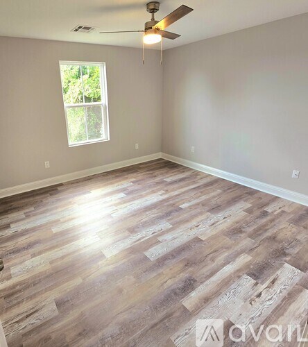 A room with wooden flooring and a ceiling fan.
