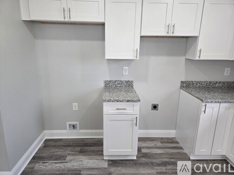 A kitchen with white cabinets and a granite countertop.