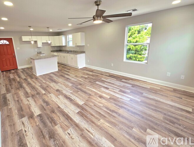 A spacious kitchen and living room with wood flooring and a ceiling fan.
