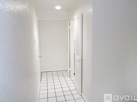 A room with wooden flooring and a doorway leading to another room.