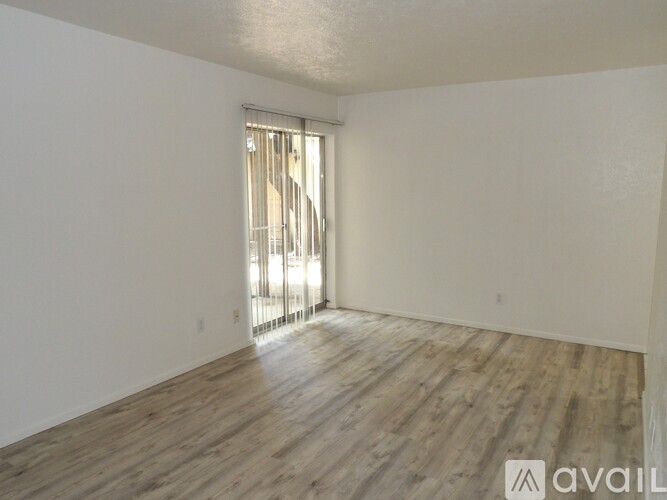 A room with wooden flooring and a window with blinds.