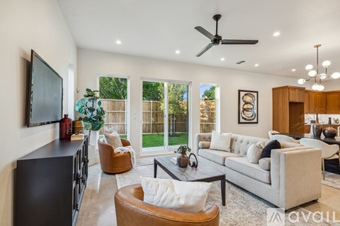 A living room with a white sofa, a brown armchair, a coffee table, and a television on the wall.