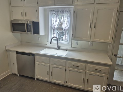 A kitchen with white cabinets and a window.