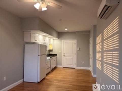 A kitchen with white appliances and wooden floors.