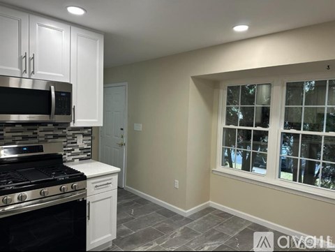 A kitchen with white cabinets and a black stove top oven.