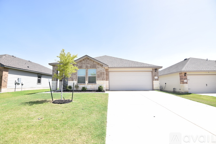 A house with a white garage door and a tree in front.