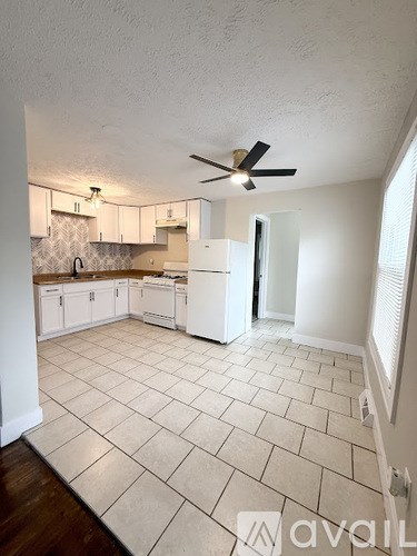 A kitchen with white cabinets and a white fridge.