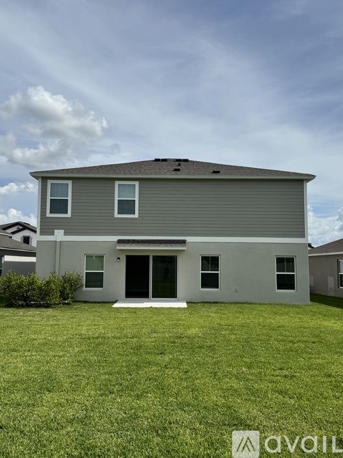 A house with a grey roof and white walls is shown with a grassy front yard.