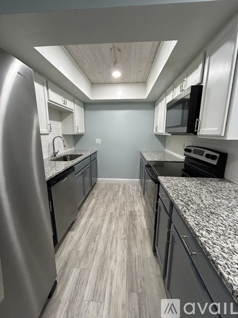 A kitchen with a stainless steel refrigerator and black appliances.