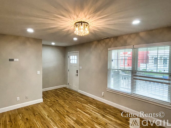 A room with wooden floors and a chandelier hanging from the ceiling.