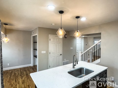 A kitchen with a sink and pendant lights.