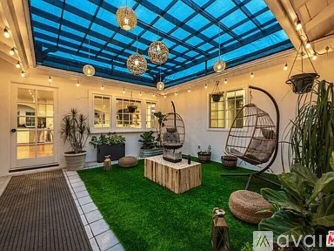 A patio with a glass ceiling and a variety of plants and furniture.
