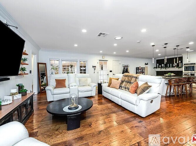 A living room with white furniture and a wooden floor.