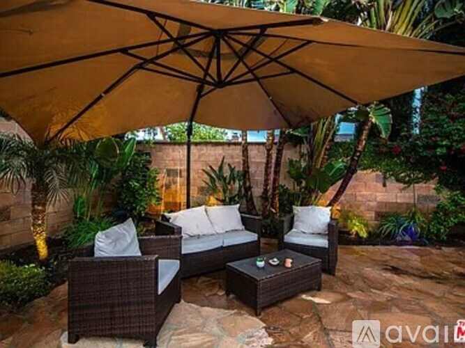 A patio with a couch, chairs and an umbrella.