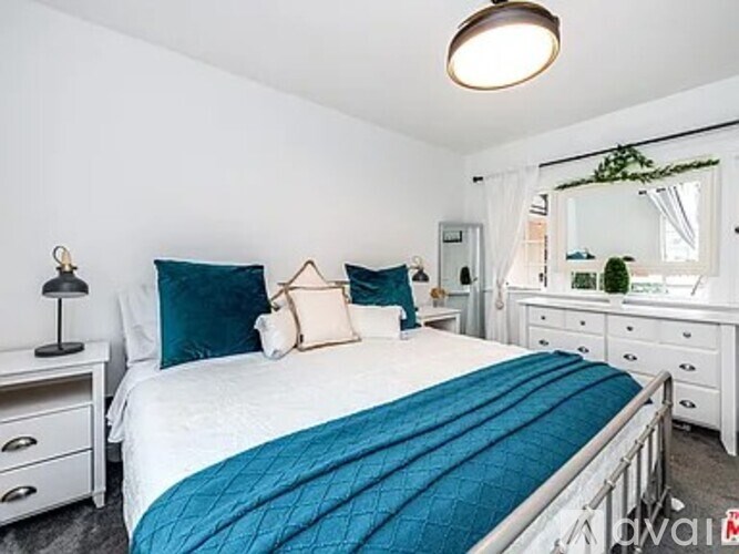 A bedroom with a white bed and blue bedspread.