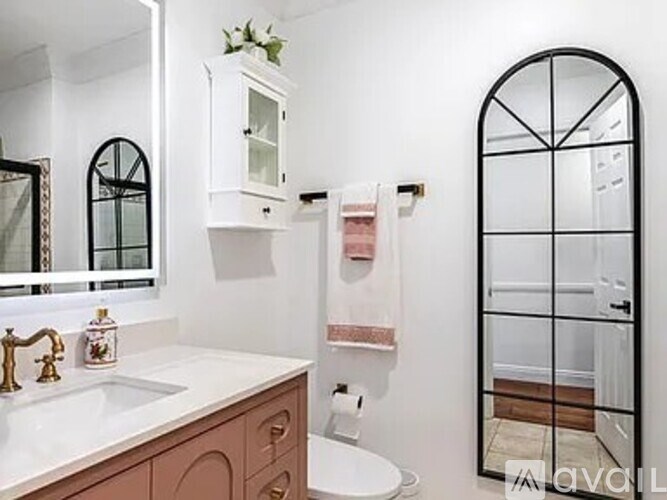 A bathroom with a sink, toilet, and a mirror.