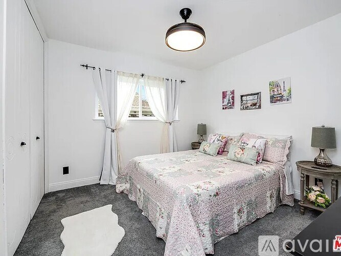 A bedroom with a bed, nightstand, and pictures on the wall.