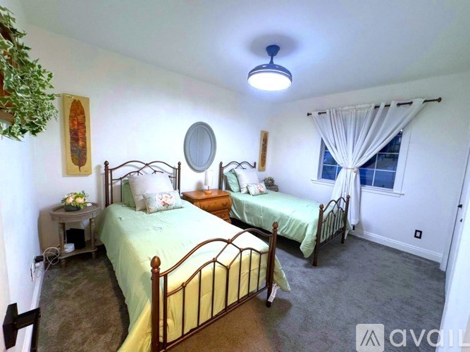 A bedroom with two beds and a window with curtains.