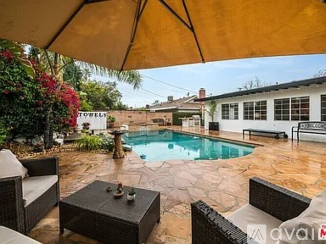 A patio with a table and chairs under a yellow umbrella.