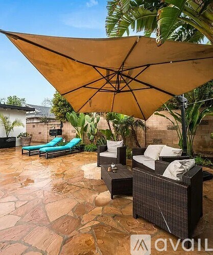 A patio with a couch, table, and umbrella.
