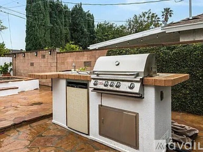 A white outdoor kitchen with a grill and sink.